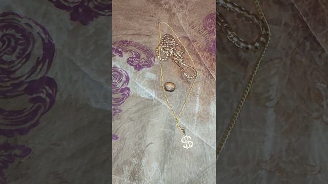 золотая цепочка ,кольцо и бусы с украшением доллар со стороны  драгоценных камней,  лежат вместе