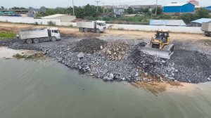 Отсыпка берега озера. Самосвалы разгружают грунт и камни, их разравнивает бульдозер