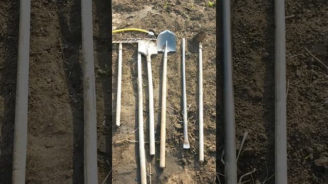 Шесть инструментов - двое грабель, две лопаты, лом и тяпка лежат на влажной земле Третьего Мая