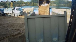 Экскаватор грузит песок в карьере.