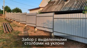 Забор с выделенными столбами из профлиста на участке с уклоном