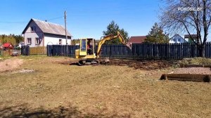 Мини-экскаватор выравнивает и планирует участок