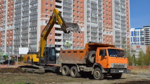 Экскаватор LOVOL FR245E2 и самосвалы КамАЗы-55111. Работа по погрузке плодородного слоя земли.