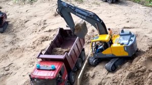 Экскаватор и самосвалы перевозят песок и камни на строительную площадку