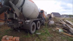 Груженый бетоном Камаз - миксер маневрирует в поле