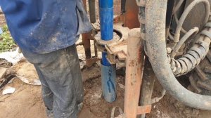 Процесс обсадки скважины пластиковыми трубами на малогабаритной буровой.