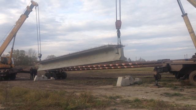 Перегрузка 18-ти метровой жби балки с балковоза оборудованного турникетами для перевозки на монтаж. смотреть онлайн