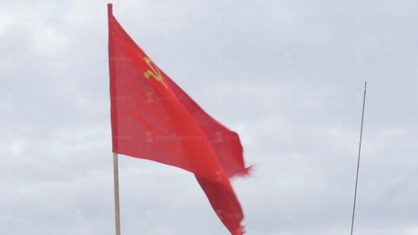 The flag of the USSR developing in the wind on a flagpole in a windy day. Flag of the Soviet Union