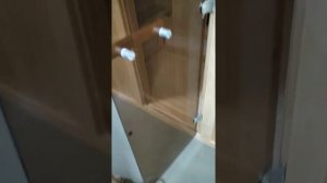 Навешиваем стеклянную дверь на петли в инфракрасной сауне.