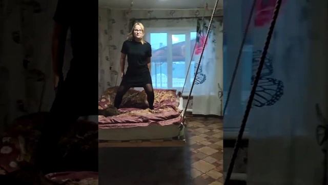 Девушка с котом качаются на кровати.