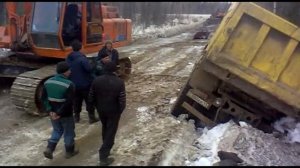 Экскаватор поднимает самосвал, который упал на бок на зимнике - как игрушку.