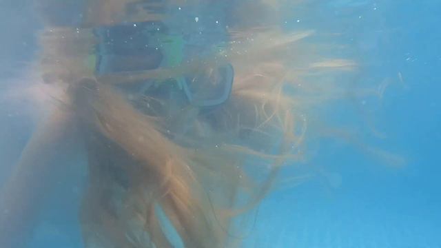 Девочка купается в бассейне